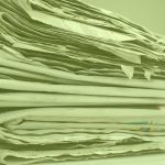 Photograph of a stack of printed newspapers with a green filter applied